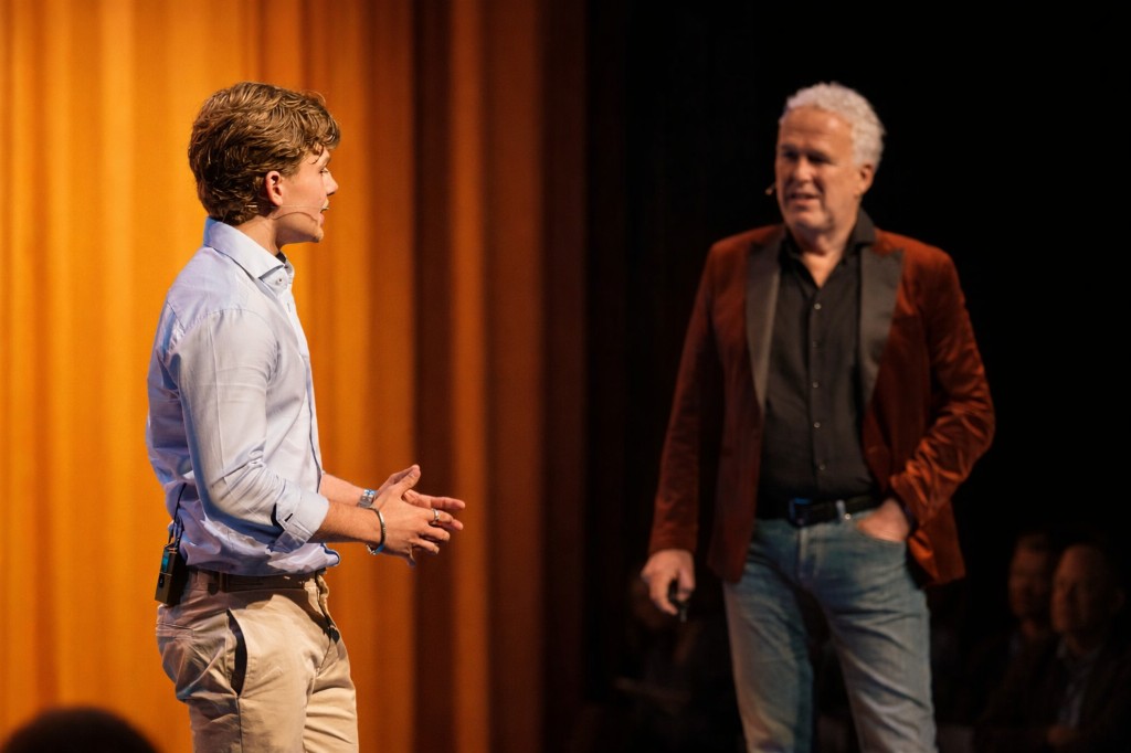 Sonny de Leeuw en Wouter de Vries op het podium tijdens een AI-presentatie, met oranje podiumdoek