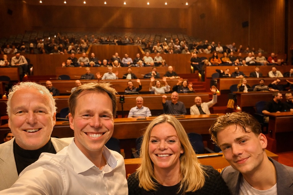 Sprekers en publiek in een volle zaal na afloop van een sessie