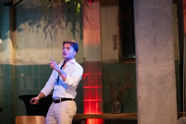 Spreker wijst naar het publiek in een industriële eventlocatie