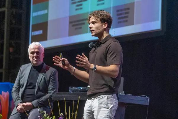 Twee sprekers op het podium bij een schema over AI-toepassingen