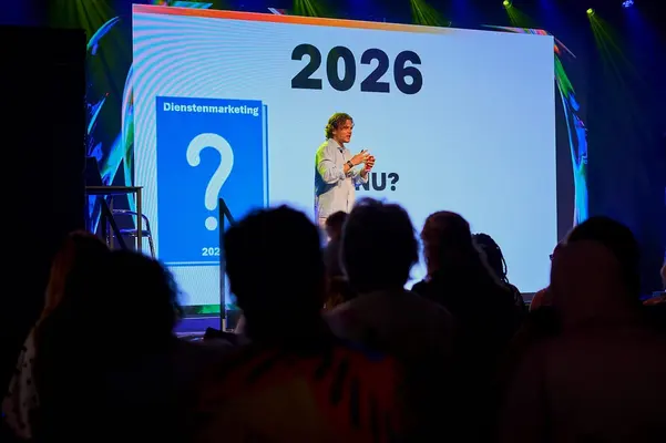 Spreker voor een groot scherm met het jaartal 2026 tijdens een lezing over AI-ontwikkelingen