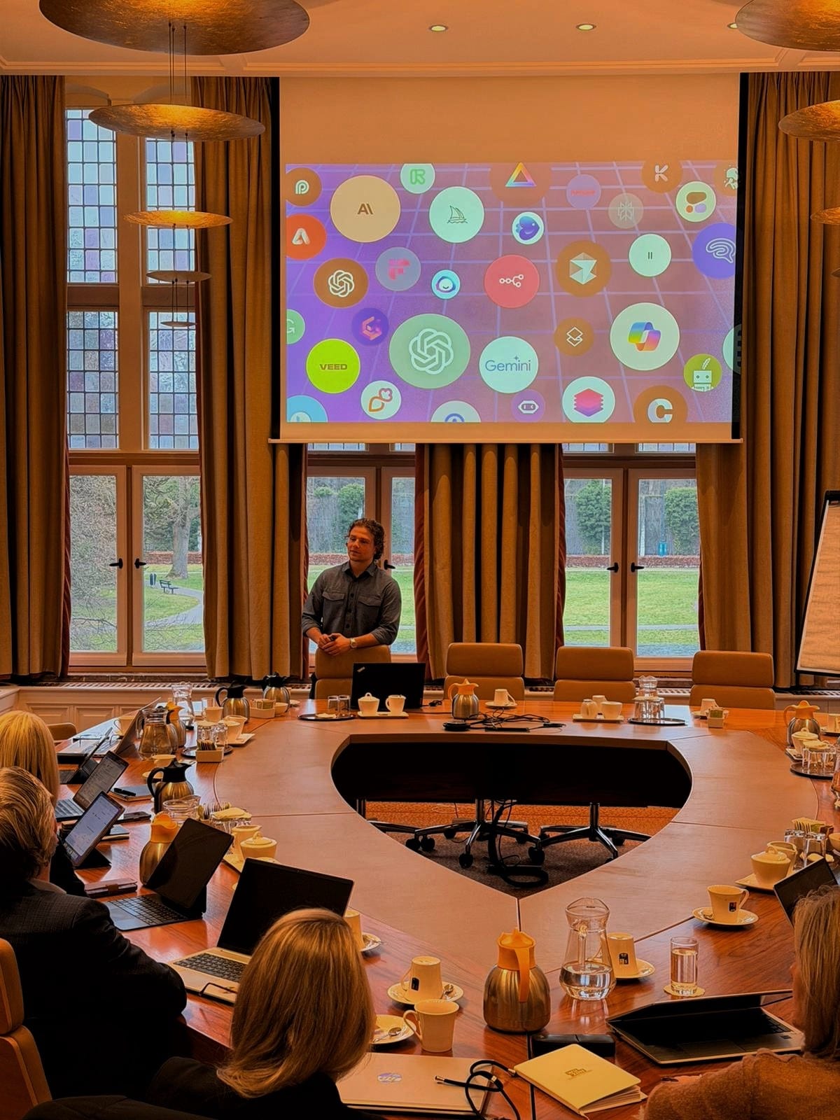 AI-sessie met een directie aan een grote vergadertafel, met AI-tools op het scherm