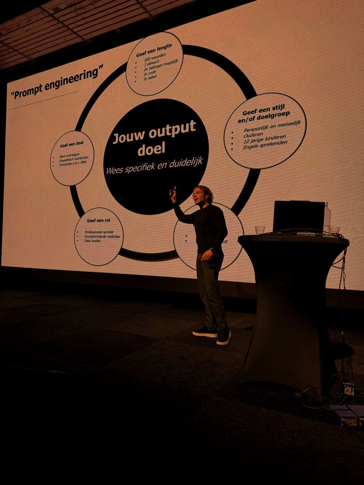 Speaker pointing at a screen explaining prompt engineering